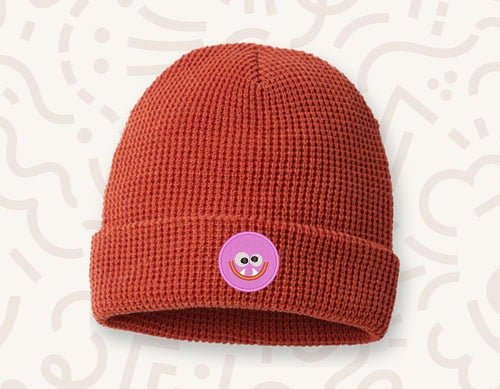Rust red knit beanie with a pink monster patch