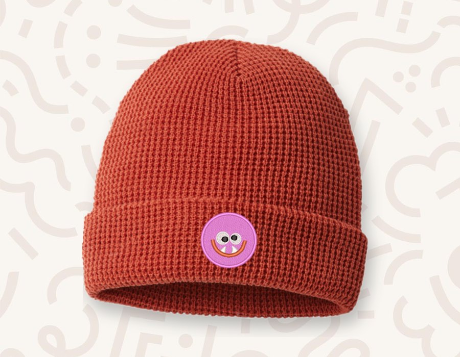 Rust red knit beanie with a pink monster patch
