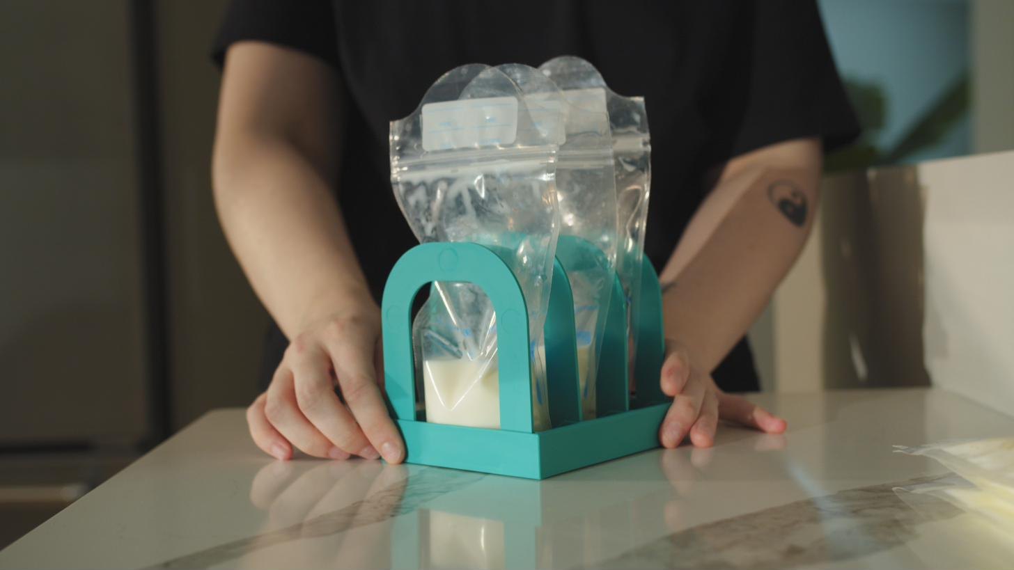 Hands placing frozen milk bags into Mylk Mate
