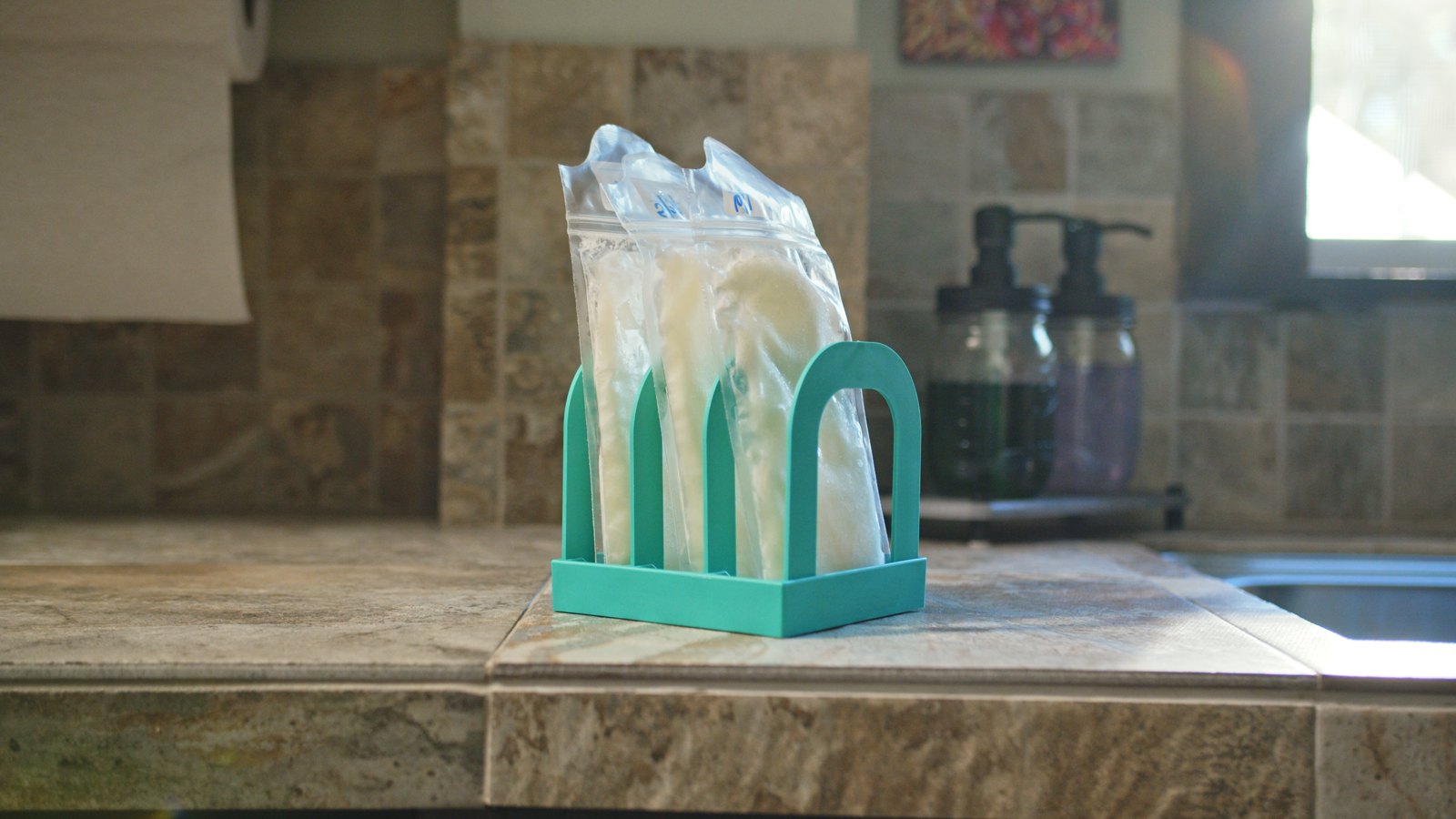 Mylk Mate holding three frozen milk bags on a kitchen counter